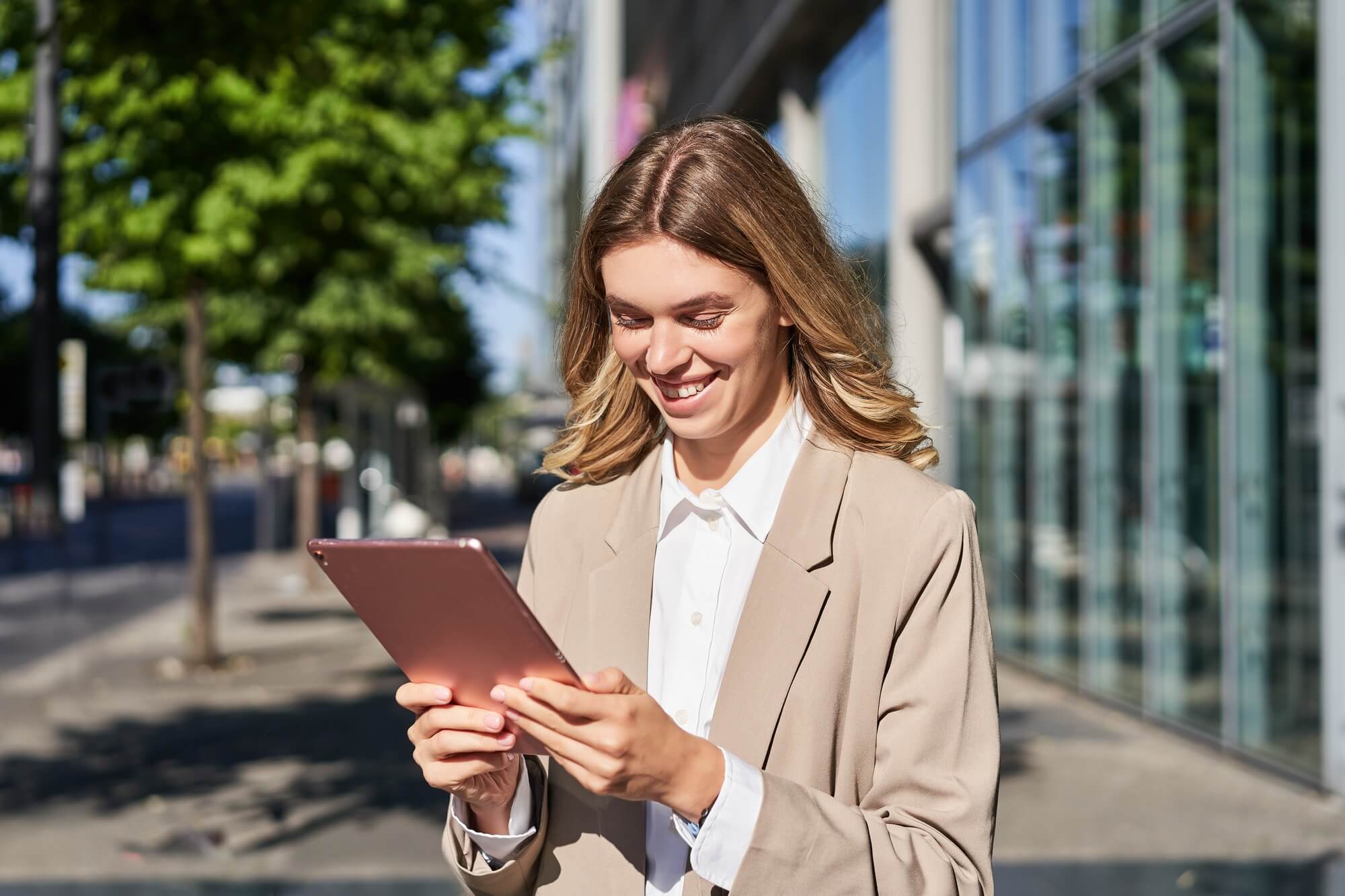 portrait-of-happy-businesswoman-smiling-holding-digital-tablet-on-street-near-office-building.jpg
